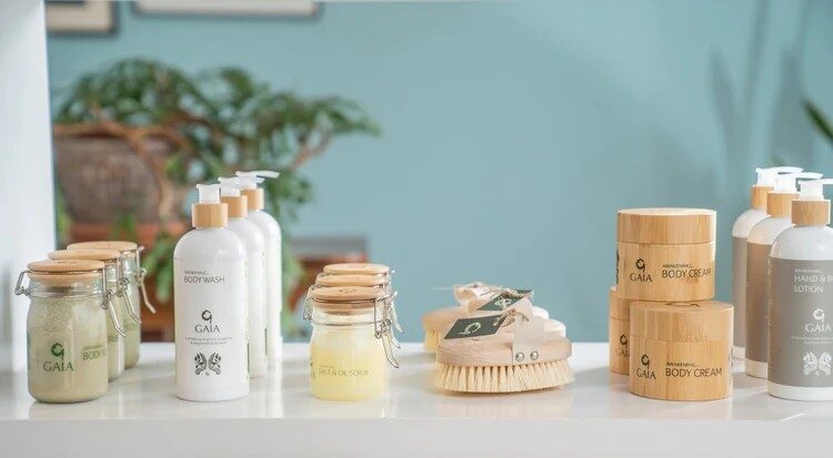 Luxurious spa products on display in a serene hotel setting, featuring body wash, creams, and scrub brushes, with lush plants.