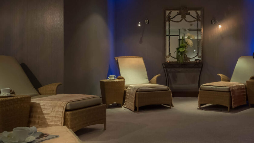 Relaxing spa lounge with cosy wicker loungers, soft lighting, and warm ambience at luxury hotel.