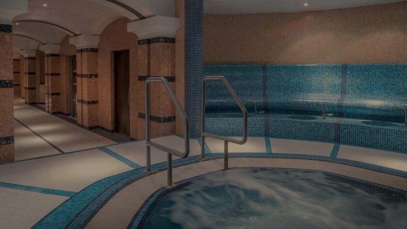Luxurious hotel spa with a bubbling Jacuzzi, inviting blue tiles, and elegant archways, offering relaxation and comfort.
